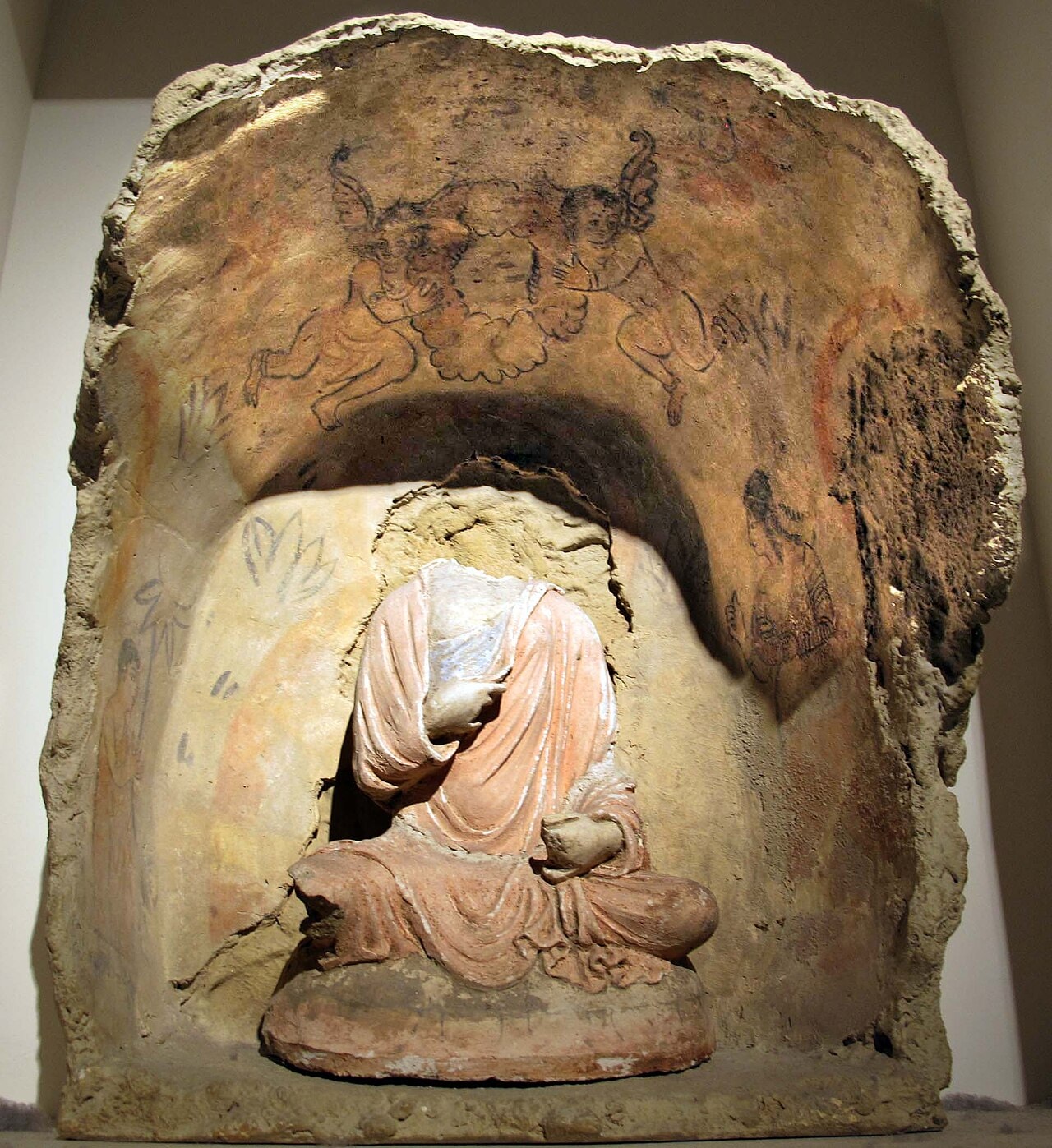 A relief of the Buddha with two small flying winged figures above him.