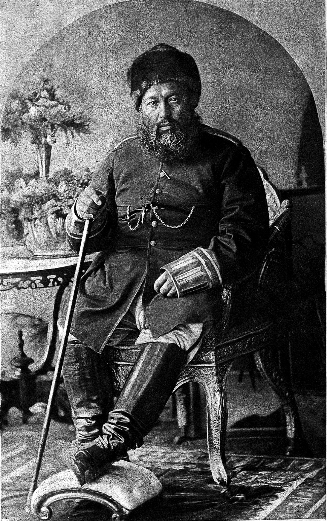 The amir seated in a carved armchair in a studio photograph taken at Rawalpindi.