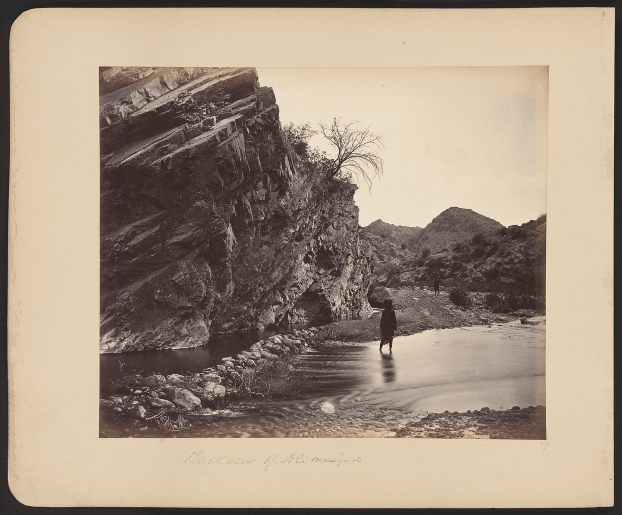 A black-and-white photograph of the fort and shrine of Ali Masjid seen from the pass below.