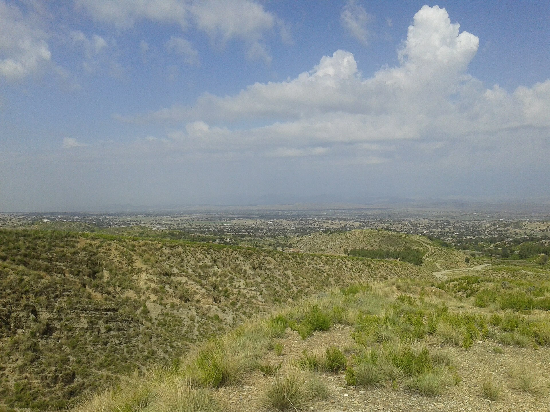 Dry hills and scrubby plain under a pale sky in Karak district