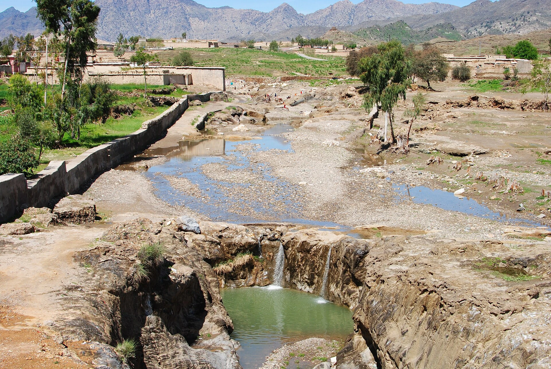 Village houses and fields below dry rocky hills