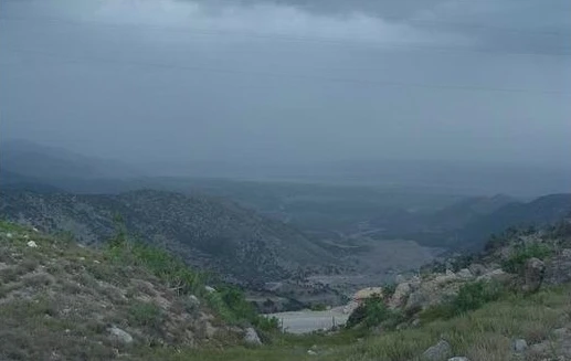 Wooded hills falling away to a valley under a grey sky