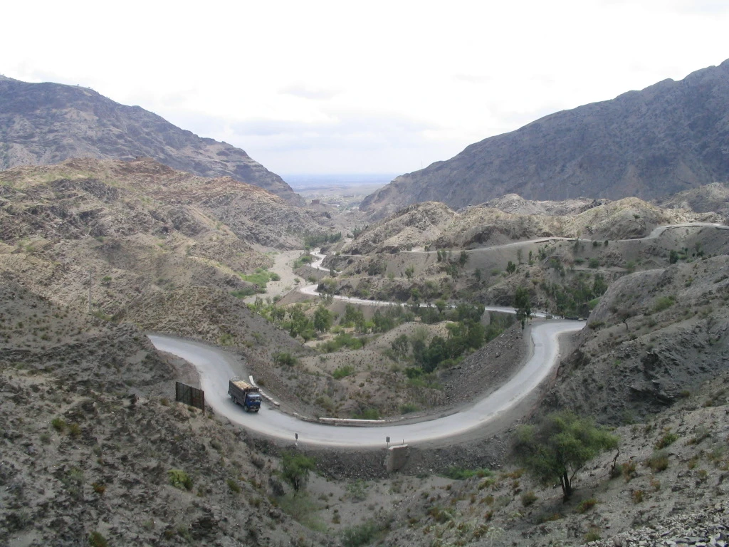 A road climbing between bare brown hills at the foot of the Khyber Pass.